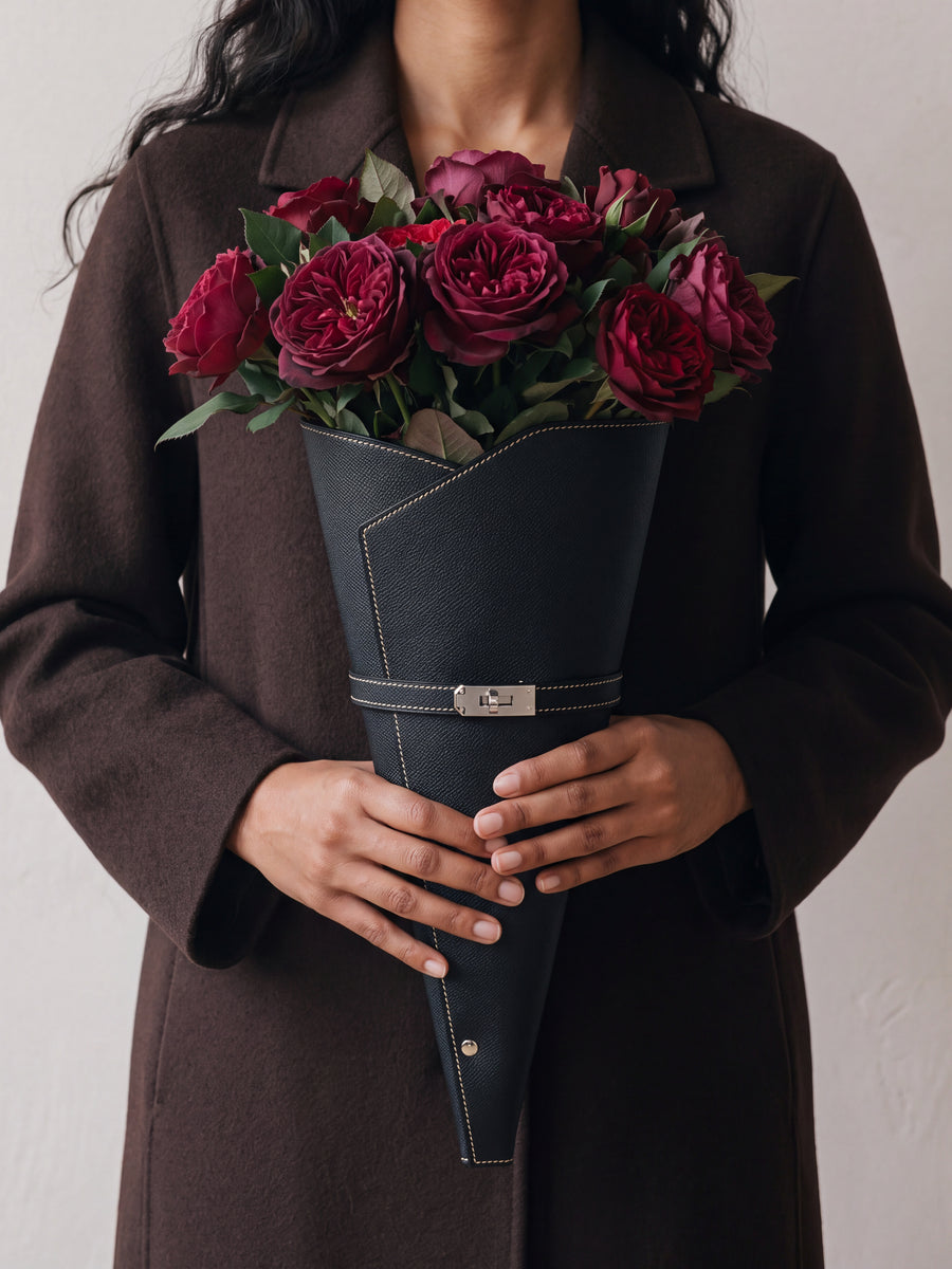 Vrouw in een café met een zwarte bloemenkoker en rode rozen
